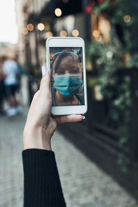 Young woman having video call talking while walking downtown wearing the face mask to avoid virus