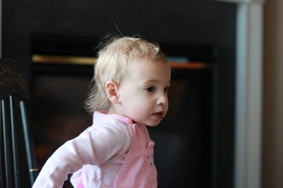 Side view of cute baby girl looking away at home