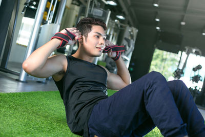 Smiling young man exercising on green carpet in gym