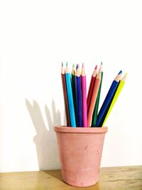 Close-up of colored pencils on table against white background