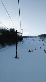 Ski lift over snow covered mountains against sky