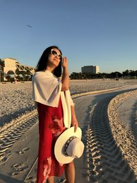 Woman standing at beach against sky