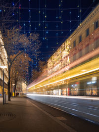 Light trails on road amidst buildings in city at night