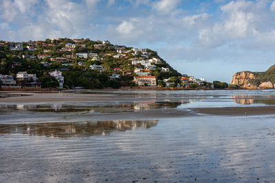 Scenic view of sea by townscape against sky