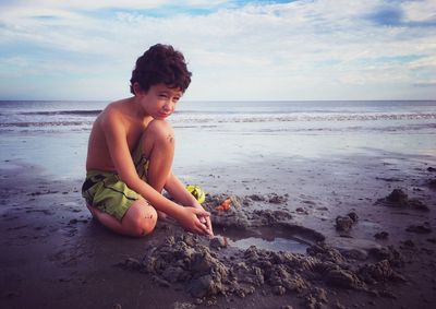 Portrait of happy boy on beach against sky