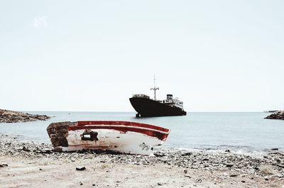 Abandoned boat on beach against clear sky