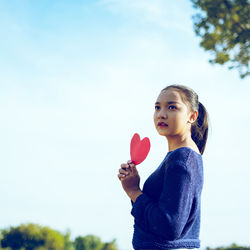 Portrait of boy holding balloons against sky