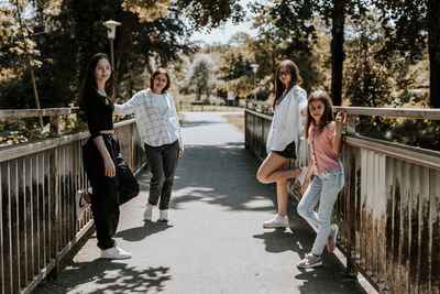 Portrait of a young mother with her three daughters in a park on a bridge.