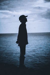 Silhouette of man standing in sea against sky