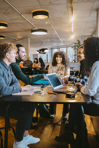 Smiling students talking while sitting at table in cafeteria