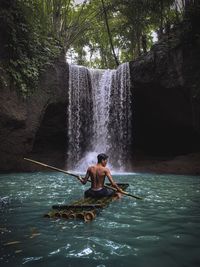 Full length of shirtless man in waterfall