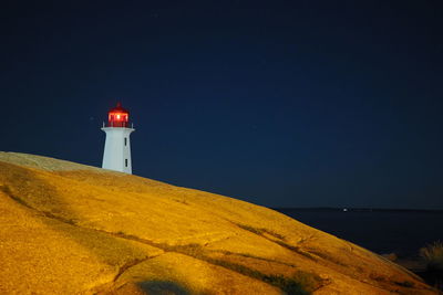 Lighthouse by sea against sky at night