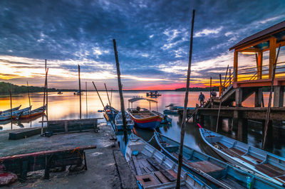 Boats moored at shore against sky during sunset