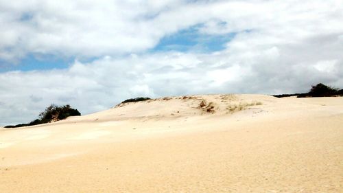 Scenic view of beach against cloudy sky