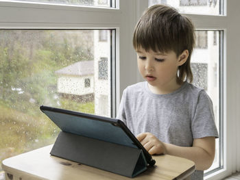 Curious boy watch cartoons on digital tablet. kid sits on floor and uses electronic device. 