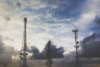 Low angle view of communications tower against cloudy sky