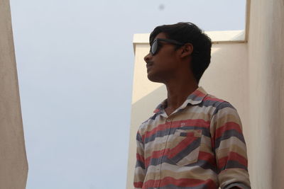 Side view of teenage boy looking away against wall at home