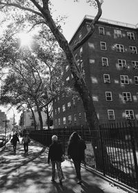 People walking on sidewalk in city against sky