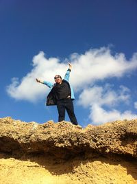 Low angle view of woman standing against blue sky