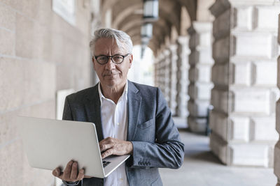 Portrait of senior businessman holding laptop