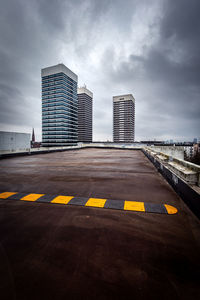 Road by buildings against sky in city