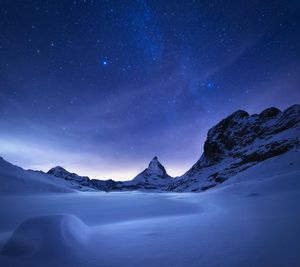 Scenic view of snowcapped mountains against sky at night