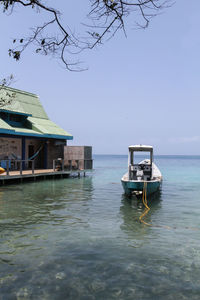 Stilt house by sea against clear sky