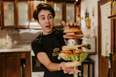 Young woman holding burger at home