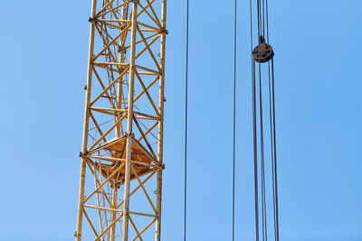 Low angle view of electricity pylon against clear blue sky