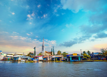 Pier over river by buildings against sky