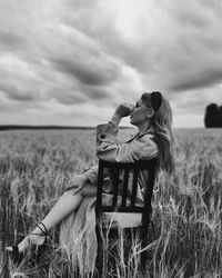 Couple kissing on field against sky