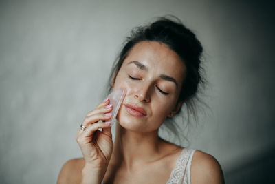 Brunette woman 30 years old doing face massage with a gouache scraper