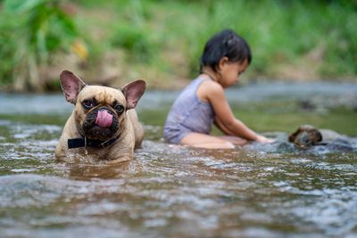 Girl sitting with dog in river