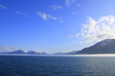 Scenic view of sea and mountains against blue sky