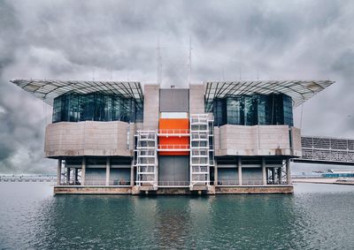 Built structure by river against sky in city