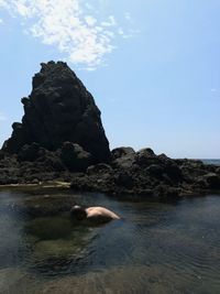 Rock formation on beach against sky