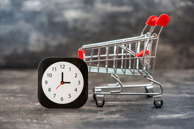 Close-up of clock and shopping cart