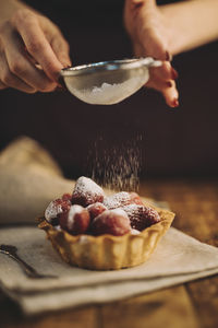 Cropped hand of person holding dessert on table