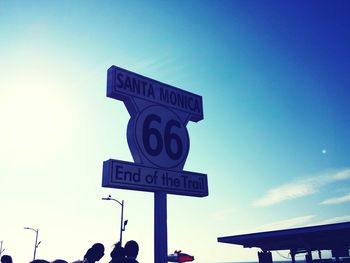 Low angle view of road sign against blue sky