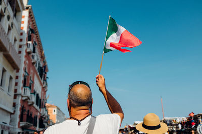 Low angle view of woman standing against clear blue sky