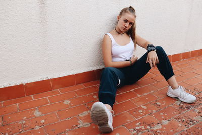 Full length of woman sitting against wall