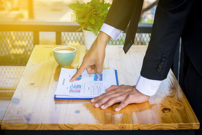 Midsection of woman holding drink served on table