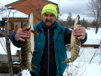 Happy fisherman with two pike in his hands