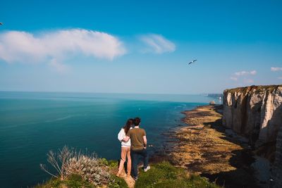 Rear view of women standing by sea against sky