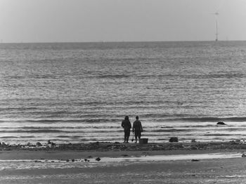 Silhouette men standing on beach against clear sky