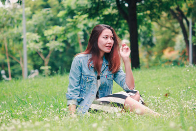 Beautiful young woman sitting on land