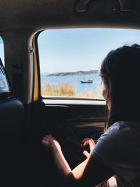 Woman looking at sea through car window