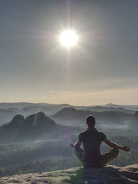 Sitting trekker in cowboy hat enjoy view with mountain sunrise.