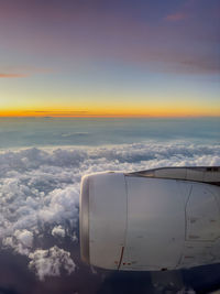 Cropped image of airplane wing against sky during sunset