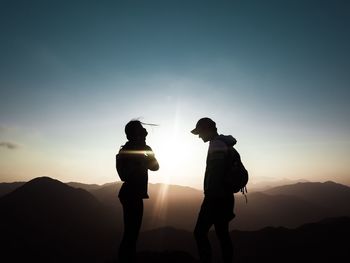 Silhouette of two men against sky